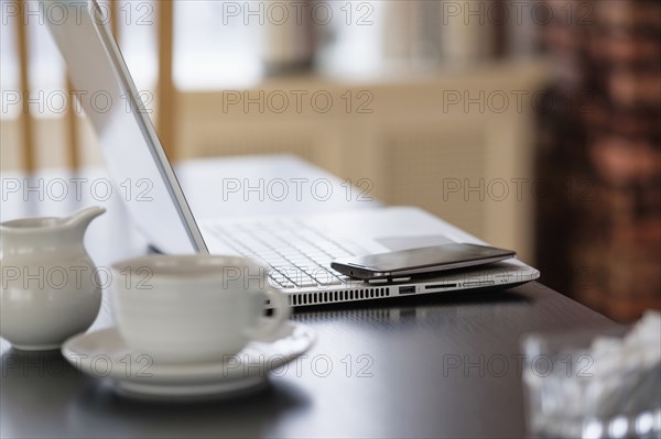 Cell phone and laptop on coffee shop table