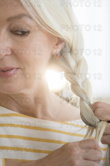 Caucasian woman braiding her hair
