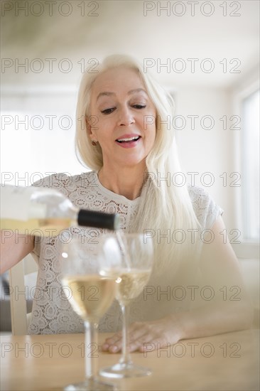 Caucasian woman pouring glasses of white wine