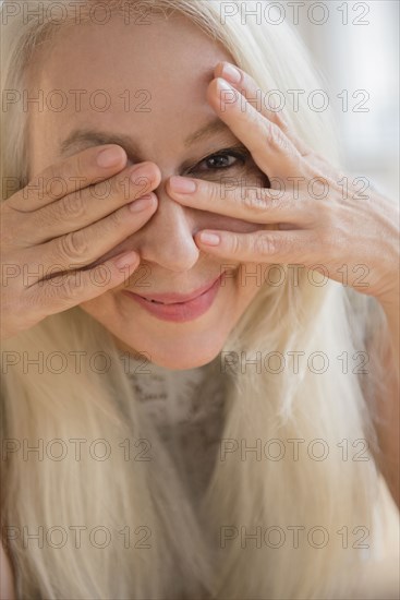 Caucasian woman peeking from behind eyes