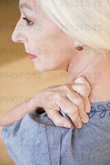 Caucasian woman rubbing sore shoulder