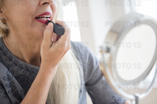 Caucasian woman applying makeup in mirror