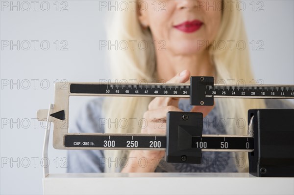 Caucasian woman weighing herself on scale