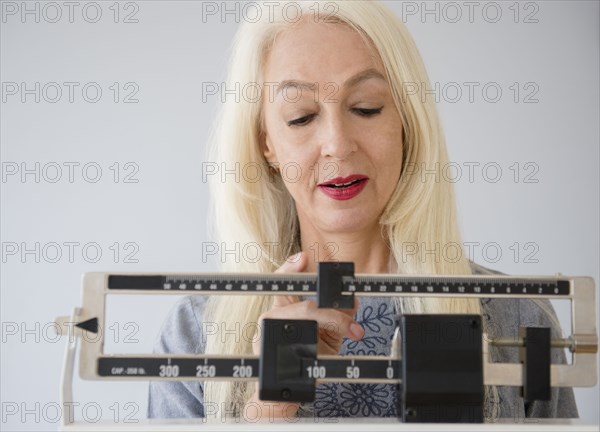 Caucasian woman weighing herself on scale