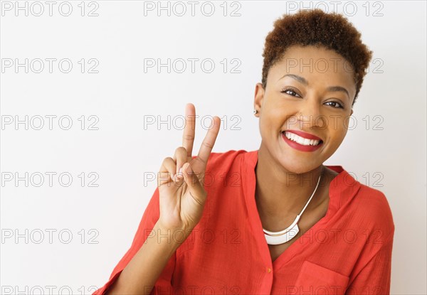 Mixed race woman making peace sign