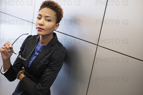 Mixed race businesswoman holding eyeglasses