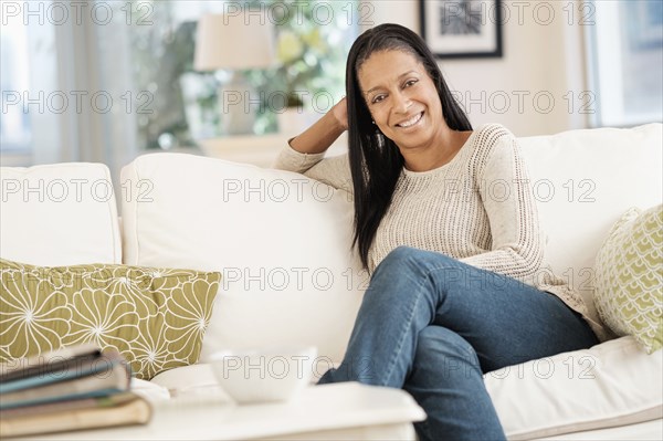 Mixed race woman smiling on sofa