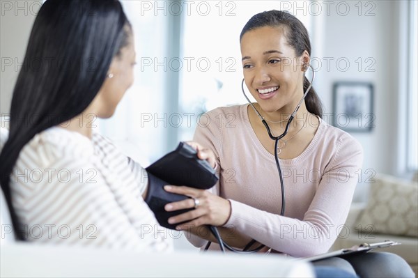 Doctor measuring blood pressure of patient in living room