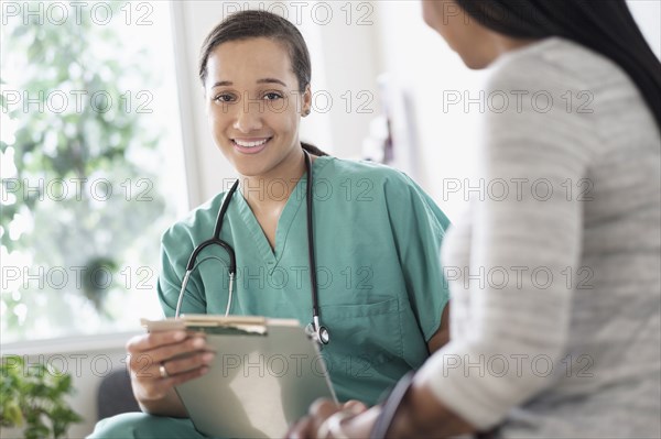 Nurse with clipboard sitting with patient