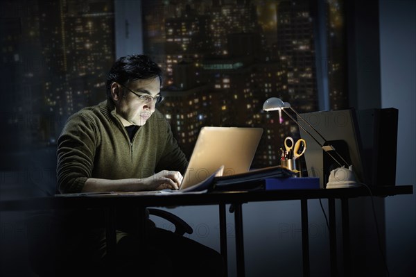 Mixed race businessman working late in office