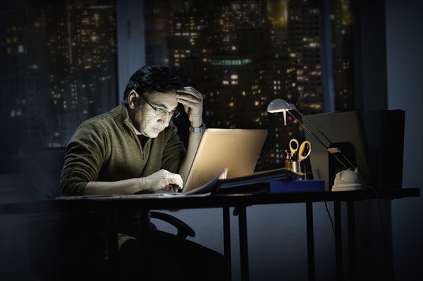 Mixed race businessman working late in office