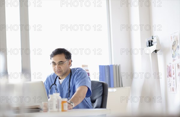 Mixed race doctor working on laptop