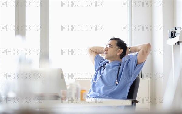 Mixed race doctor relaxing at desk