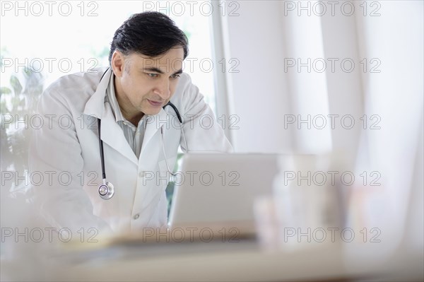 Mixed race doctor working on laptop