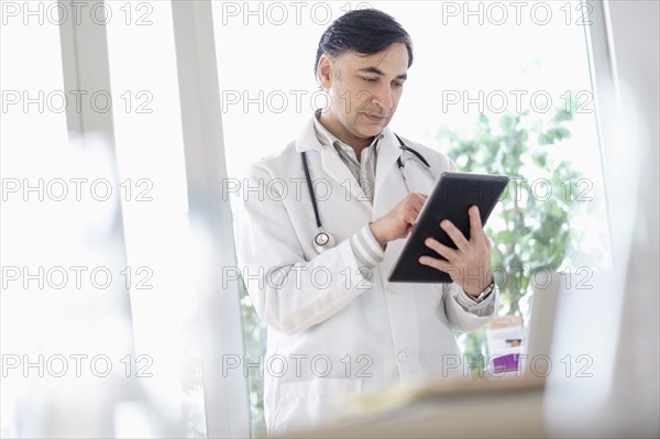 Mixed race doctor using digital tablet