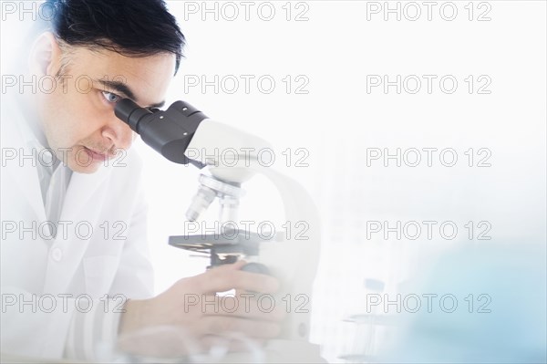 Mixed race scientist using microscope