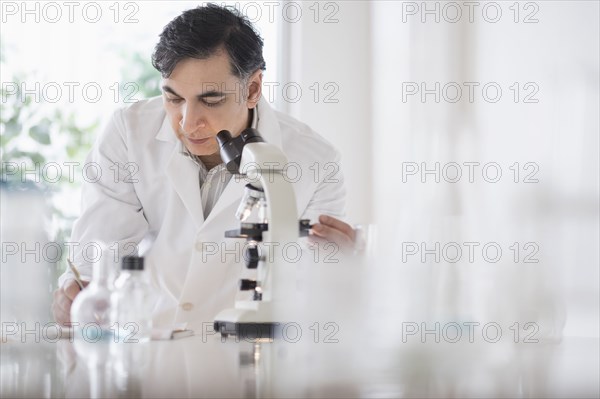 Mixed race scientist using microscope in laboratory