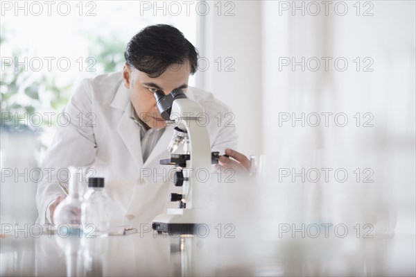 Mixed race scientist using microscope in laboratory