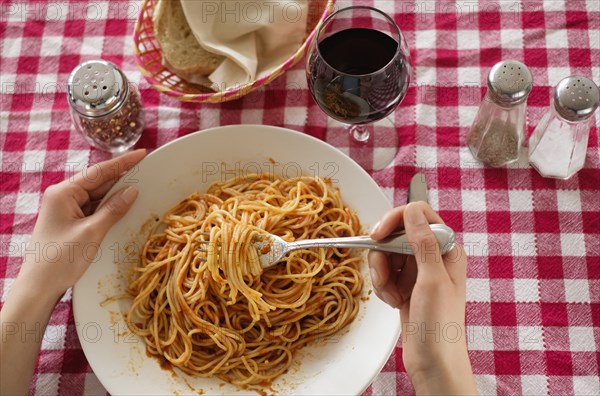 Hispanic woman eating plate of pasta