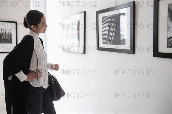 Hispanic woman admiring art in gallery