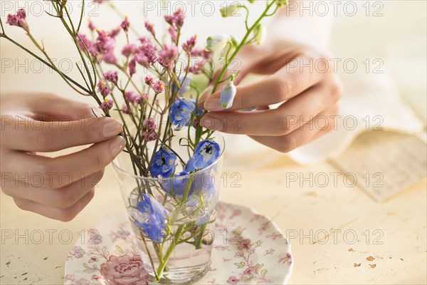 Hispanic woman arranging flowers in glass cup
