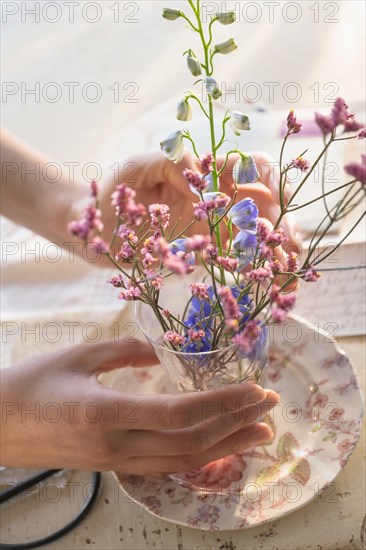 Hispanic woman arranging flowers in glass cup