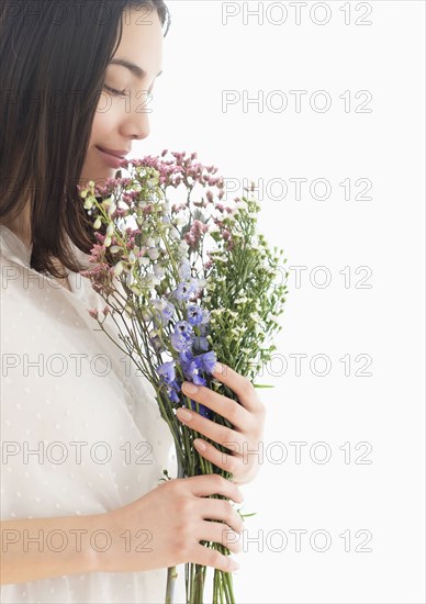 Hispanic woman smelling bouquet of flowers