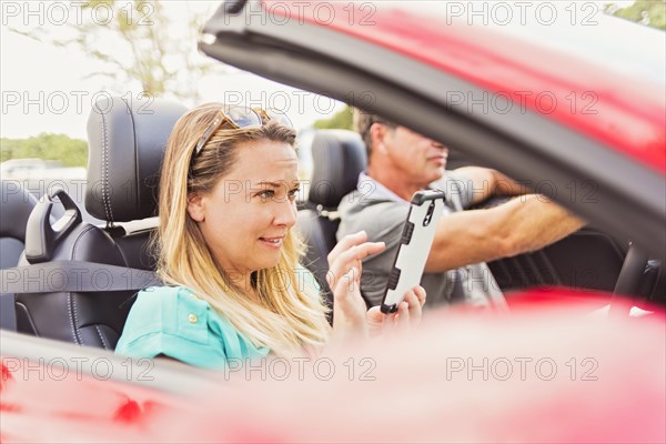 Caucasian woman using cell phone in convertible