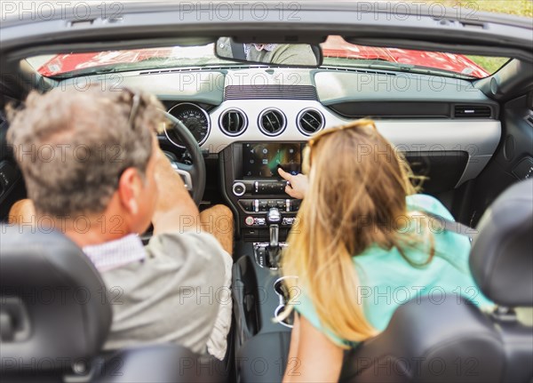 Caucasian couple driving convertible