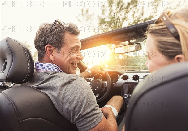 Caucasian couple driving convertible