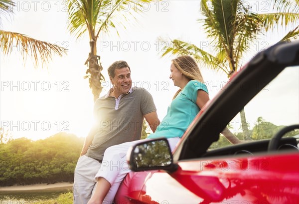 Caucasian couple sitting on convertible