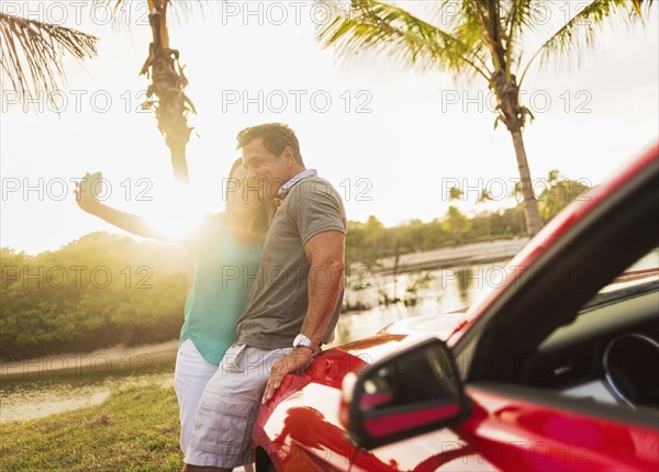 Caucasian couple taking selfie on convertible