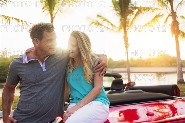 Caucasian couple sitting on convertible