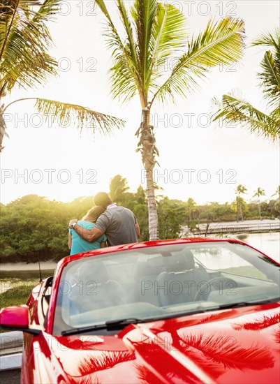 Caucasian couple hugging on convertible