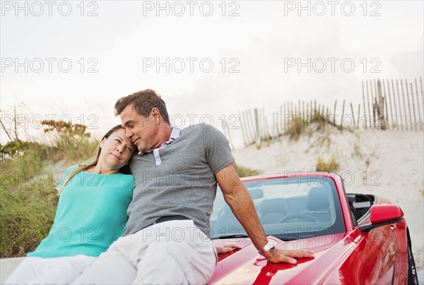 Caucasian couple sitting on convertible