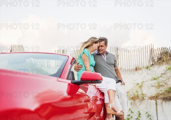 Caucasian couple sitting on convertible