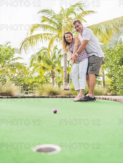 Caucasian couple playing miniature golf