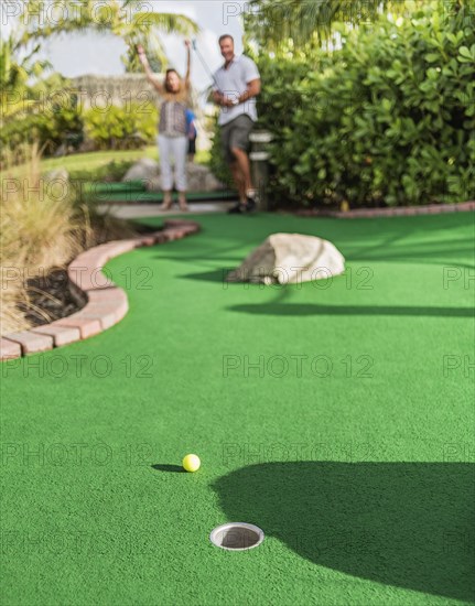 Caucasian couple playing miniature golf