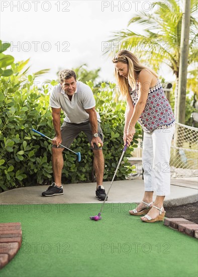 Caucasian couple playing miniature golf