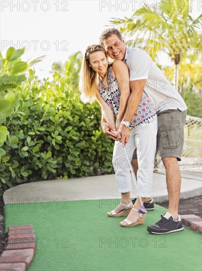 Caucasian couple playing miniature golf