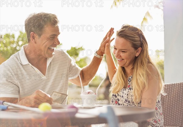 Caucasian couple high-fiving at outdoor table