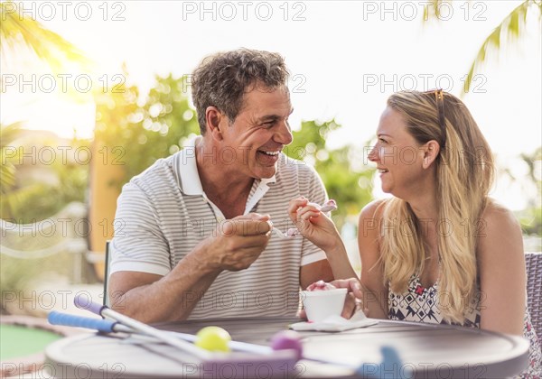 Caucasian couple eating ice cream at outdoor table