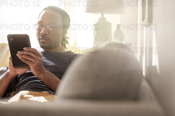 Black man using digital tablet on sofa