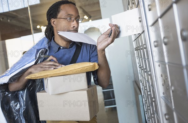 Black man gathering mail from post office box