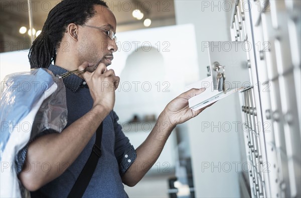 Black man gathering mail from post office box