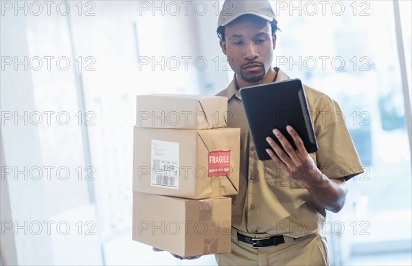 Black delivery man using digital tablet