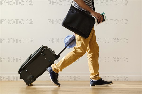 Black businessman rolling luggage