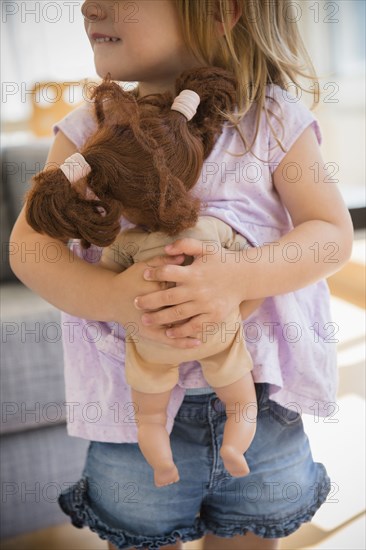 Caucasian girl hugging doll