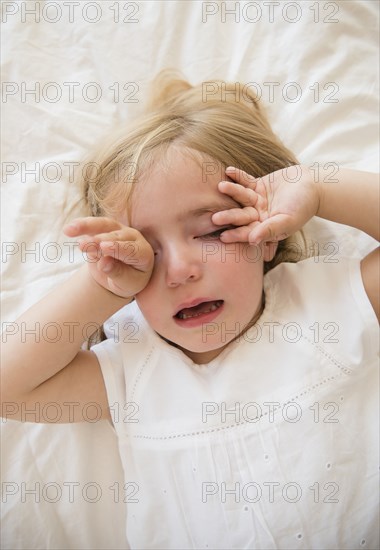 Caucasian girl crying on bed
