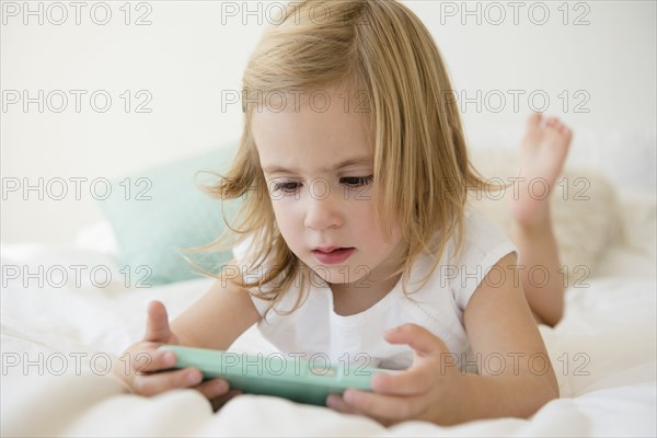 Caucasian girl using cell phone on bed